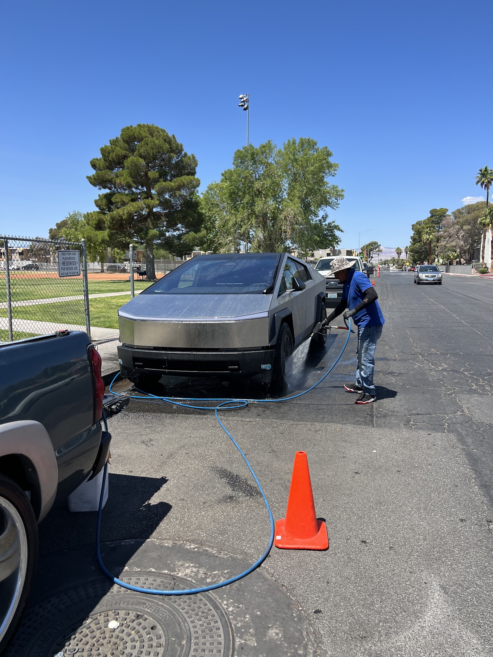 Detailer pressure-washing a Tesla Cybertruck on the street