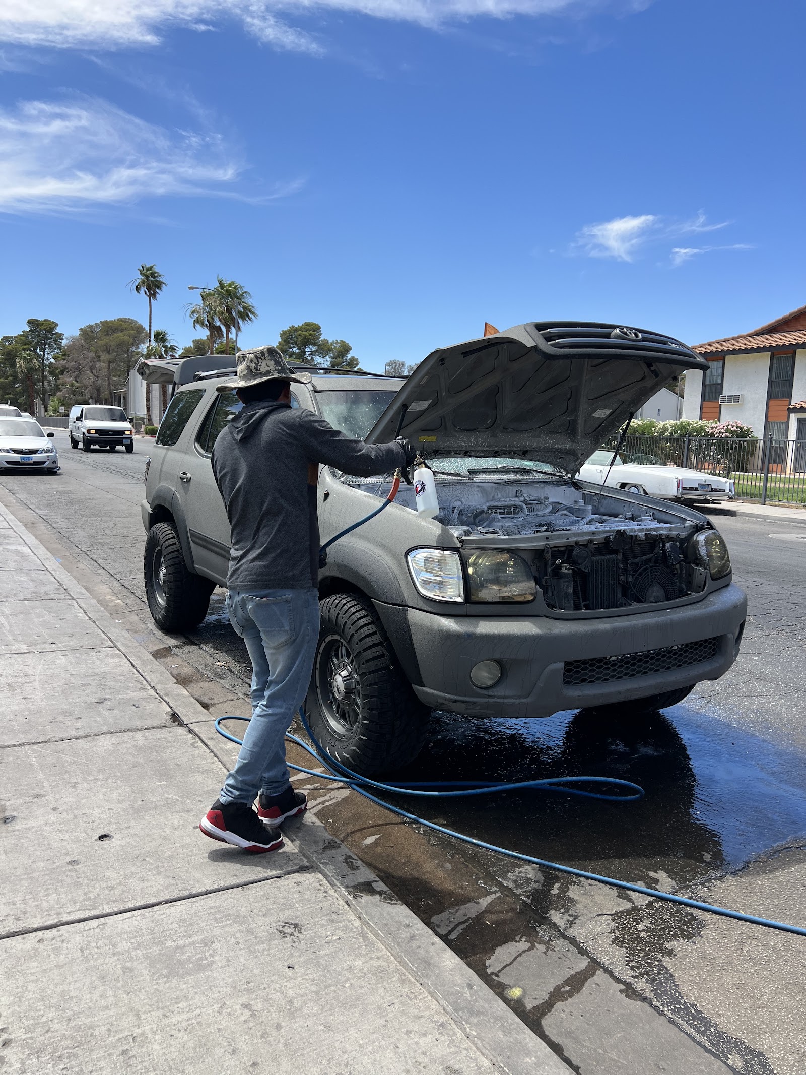 Detailer cleaning the engine bay of a Toyota Sequoia with the hood open